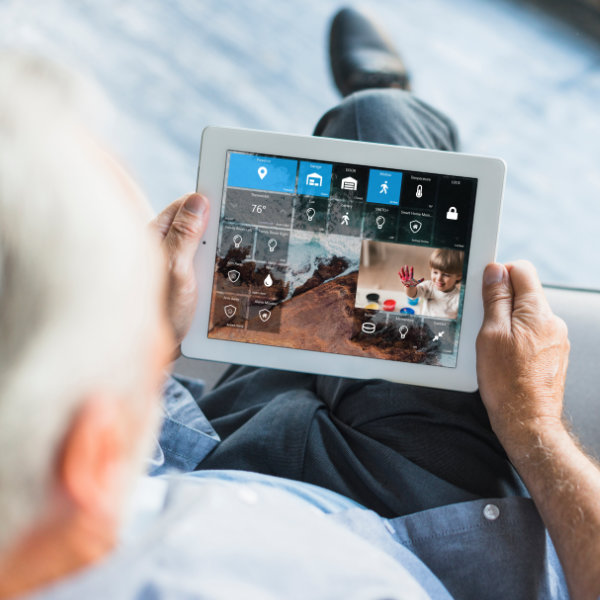 An elder man hold a ipad with smart home dashboard displayed.
